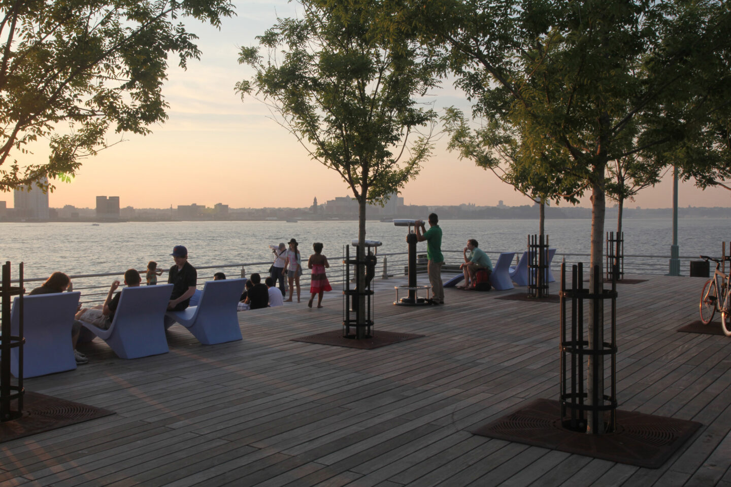 People gathered at the end of Pier 25 looking out at the sunset on the Hudson river