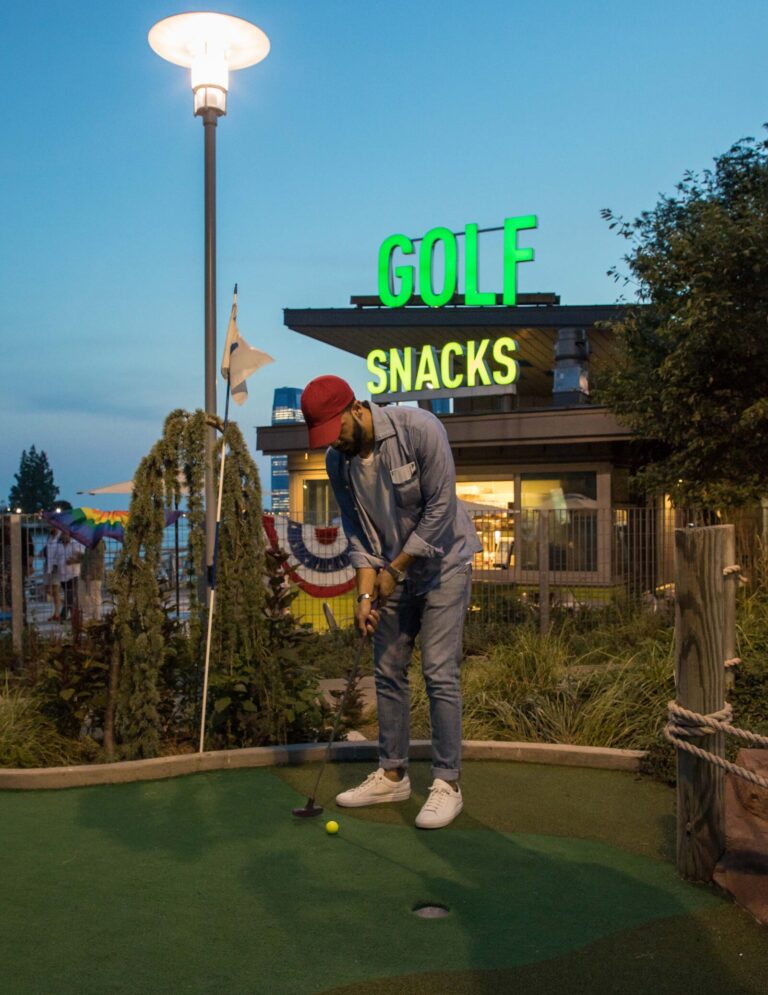 A mini-golf player focuses on putting the ball into the hole