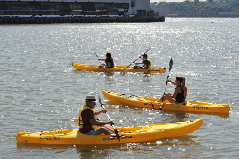 People in yellow kayaks move about the River
