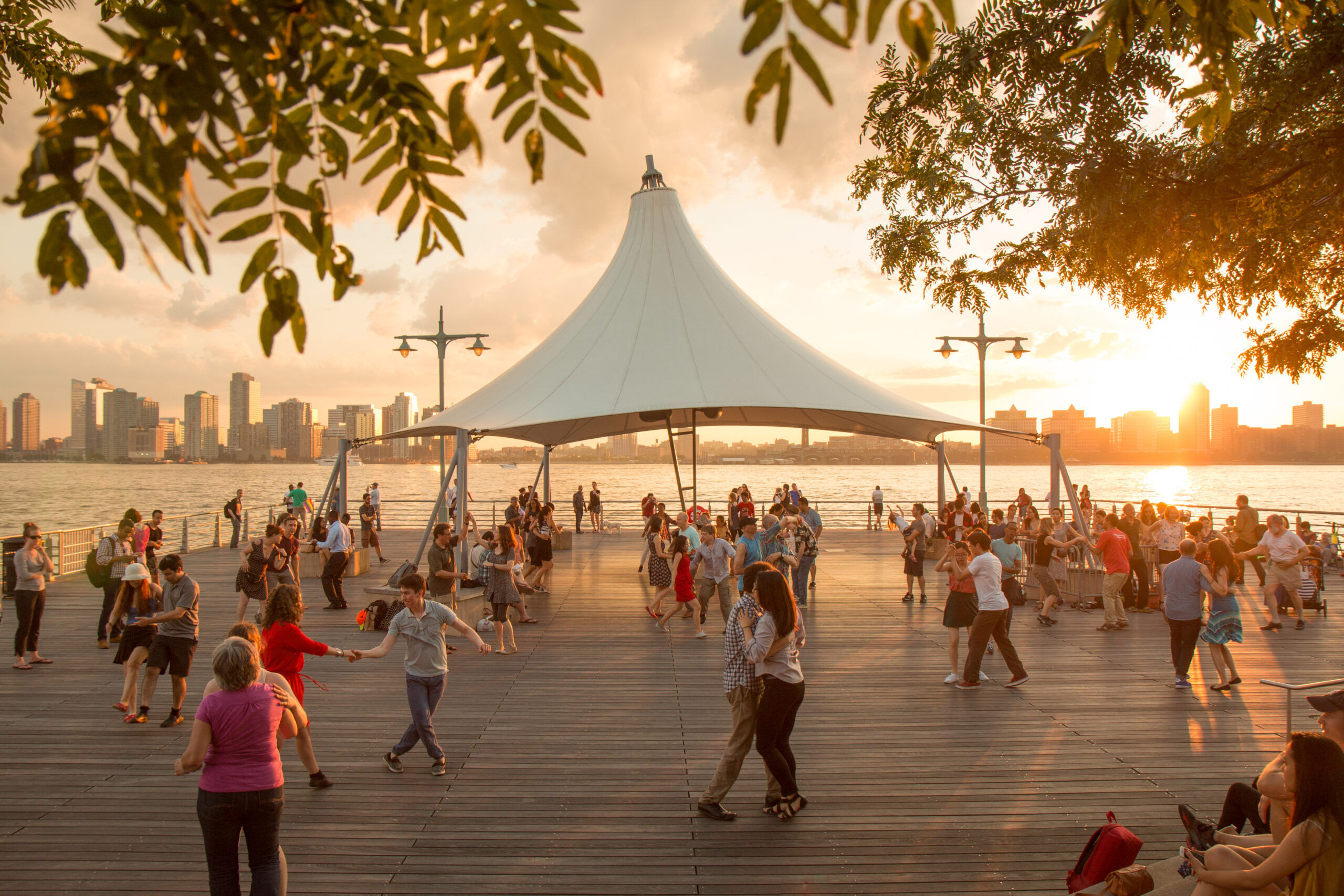 Sunset Salsa participants partner up and dance around under the canopy at sunset on Hudson River Park's Pier 45