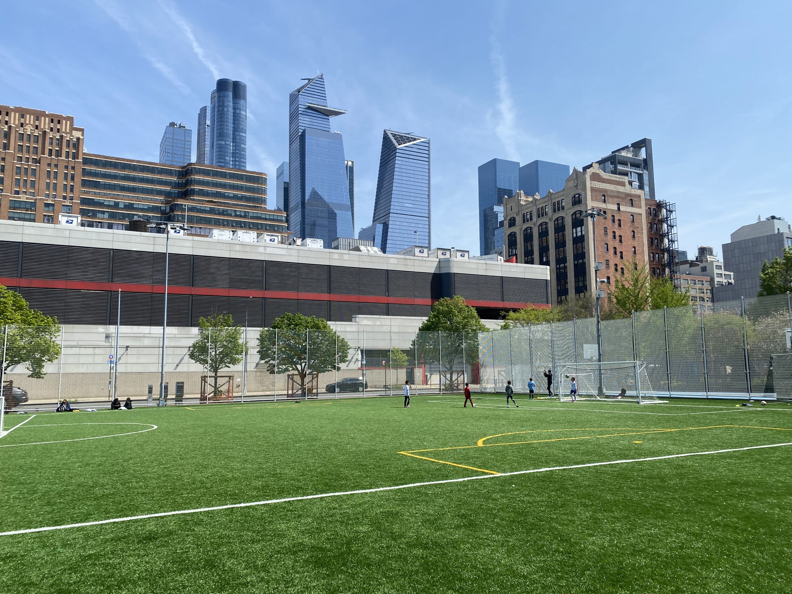 The turf athletic field at Chelsea Waterside Park, with Hudson Yards skyscrapers visible in the distance