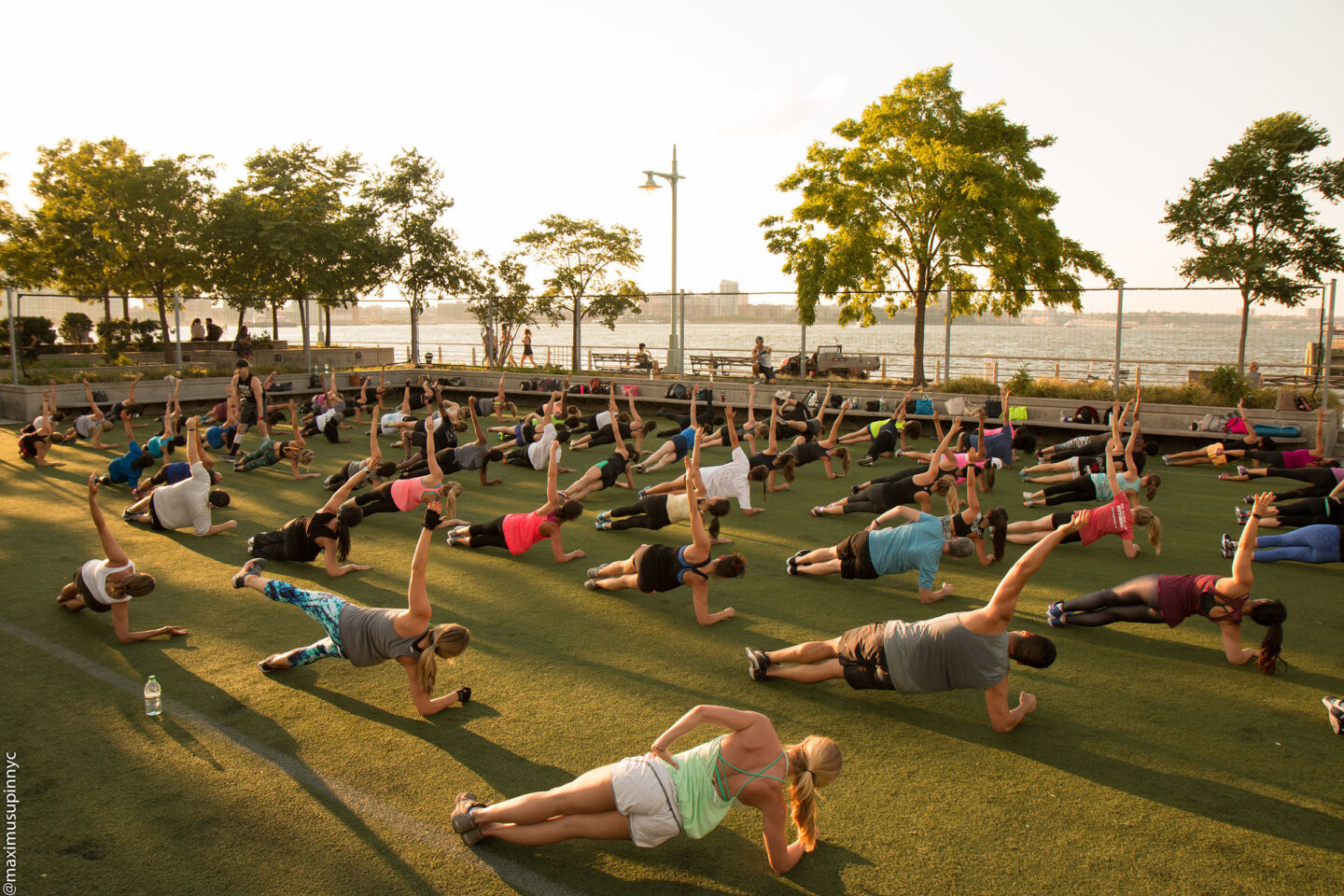 A large group of yoga enthusiasts begin on the lawn at Pier 25