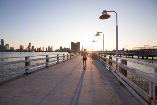 a jogger heads down Pier 34 as the sun sets at Hudson River Park