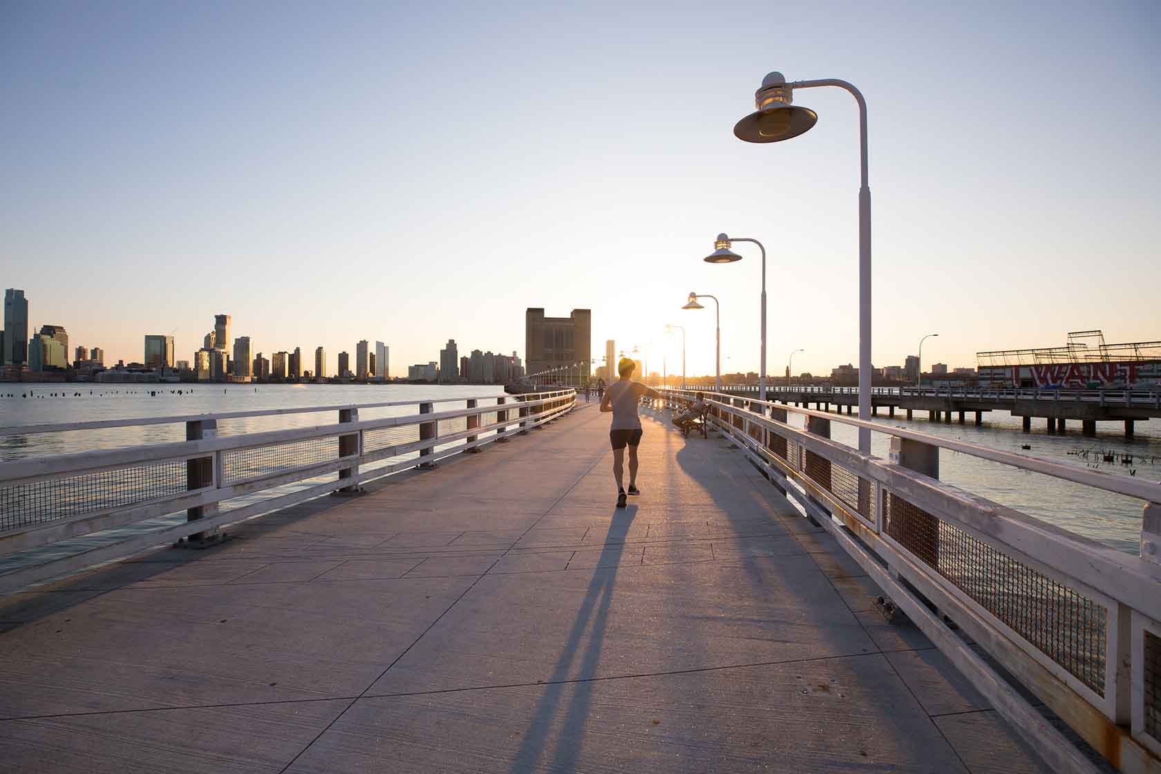 a jogger heads down Pier 34 as the sun sets at Hudson River Park