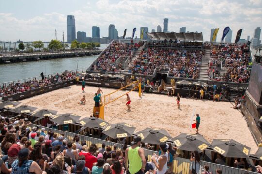 An overhead view of the whole sandy volleyball court with the two teams on either side of the net