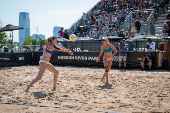 A volleyball player rushes to hit the ball over the net