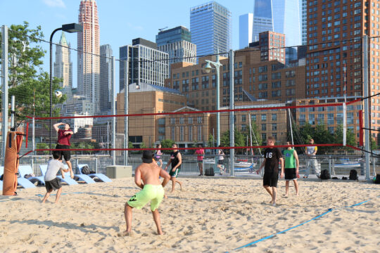 Beach volleyball players ready for the ball coming over the net at Hudson River Park's Pier 25