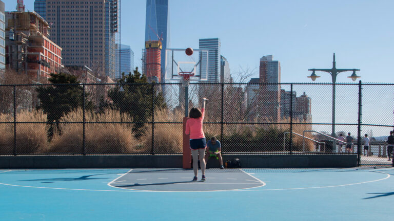 A basketball player shoots a basket on the Canal Street Basketball Courts