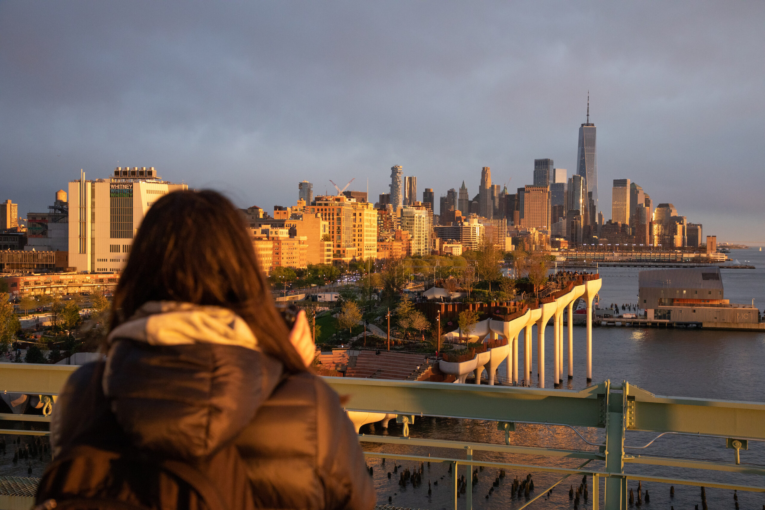 A person taking in the view of Little Island and the Lower Manhattan skyline from the Pier 57 Rooftop Park