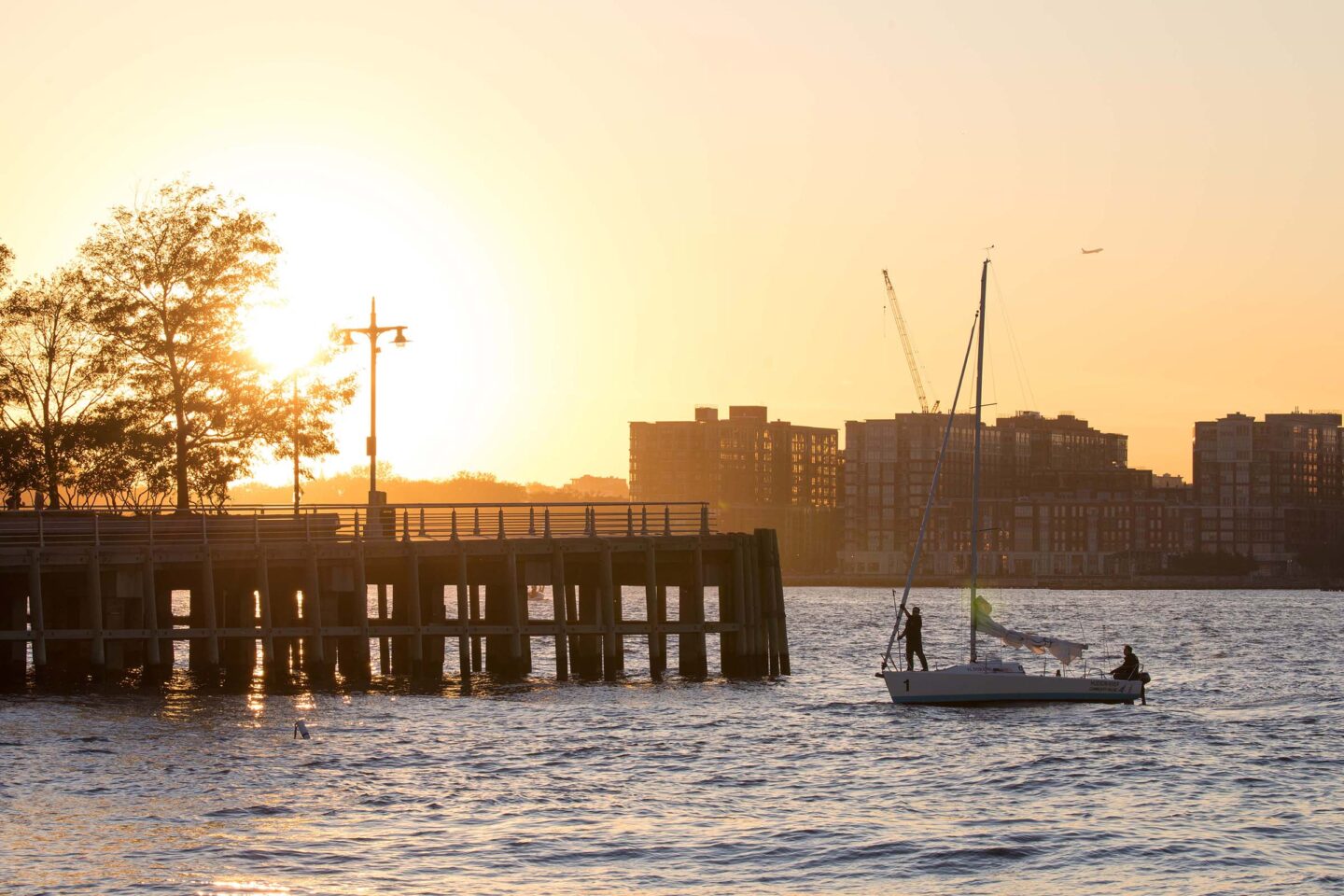The sun sets as a sailor moors near Pier 64