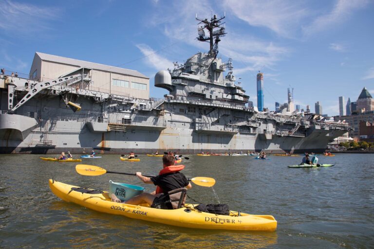 Kayakers paddle in the water near the USS Intrepid at Pier 86