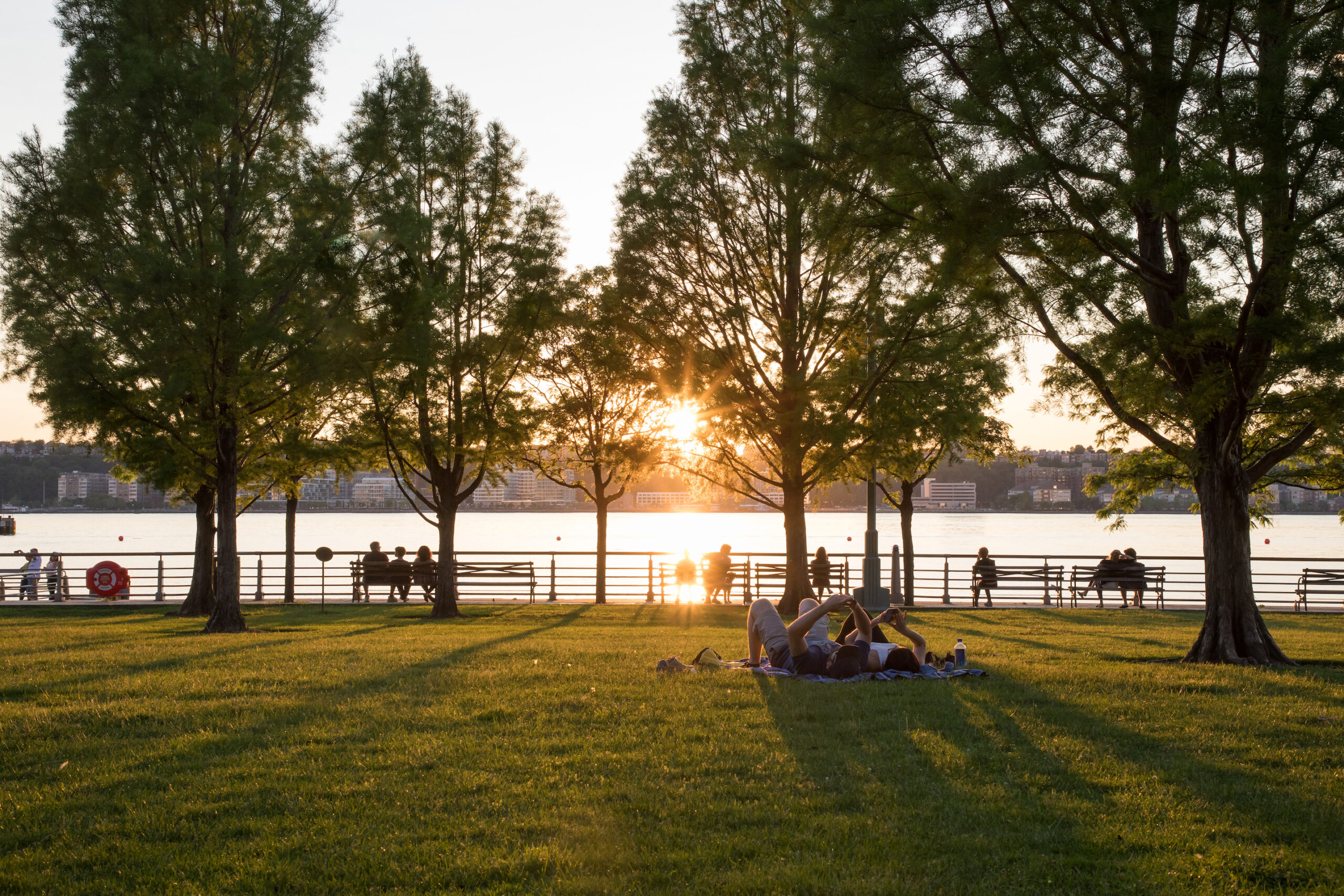 The sun sets as Park Visitors sit on the Clinton Cove lawn bowl at Hudson River Park