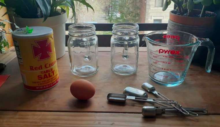 A tin can, egg, two glass mason jars and measuring cups