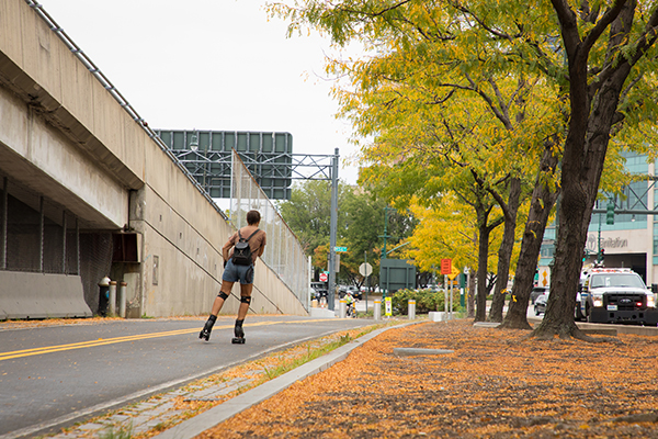 A roller blader heads down the bikeway as orange leaves cover the ground