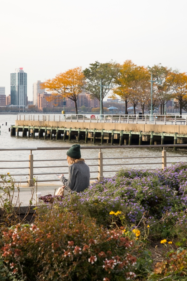 A Park visitor sits and enjoys Hudson River Park while on the phone