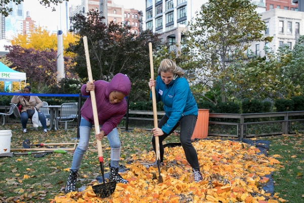 Two volunteers help clean up all the smashed pumpkins to go into the composter in Hudson River Park