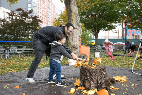 A dad helps his child smash one of the many pumpkins at Pumpkin Smash in Hudson River Park