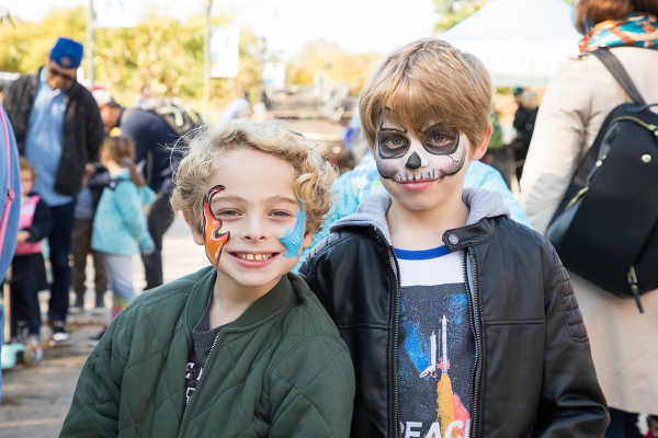 Friends have face paint of skulls and flames on their cheeks