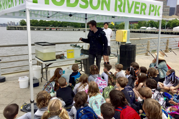 A hudson river park educator shows a fish to students