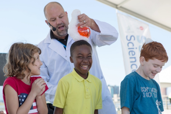 An excited kid waits for the scientist to pour goo on his head