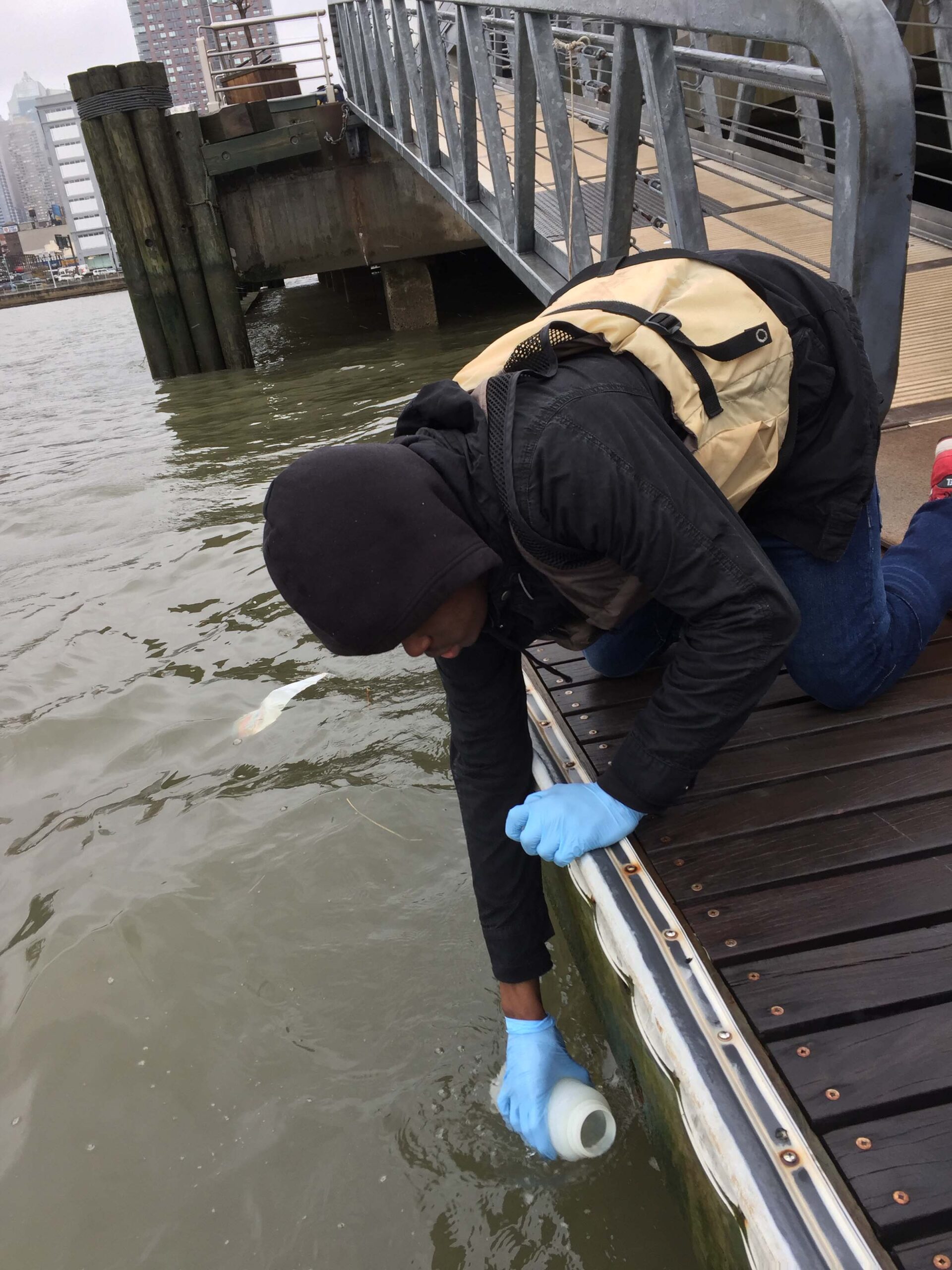 A scientist fills a jar with water for sampling