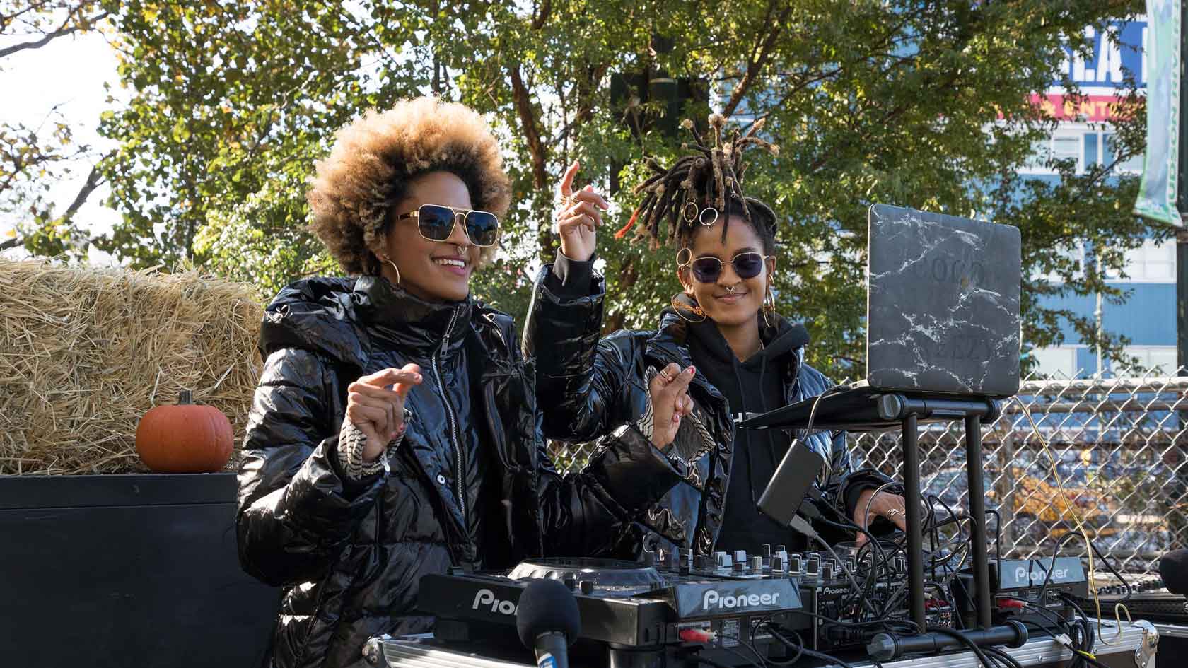 DJ's Coco and Breezy dressed in black jackets play music for the crod