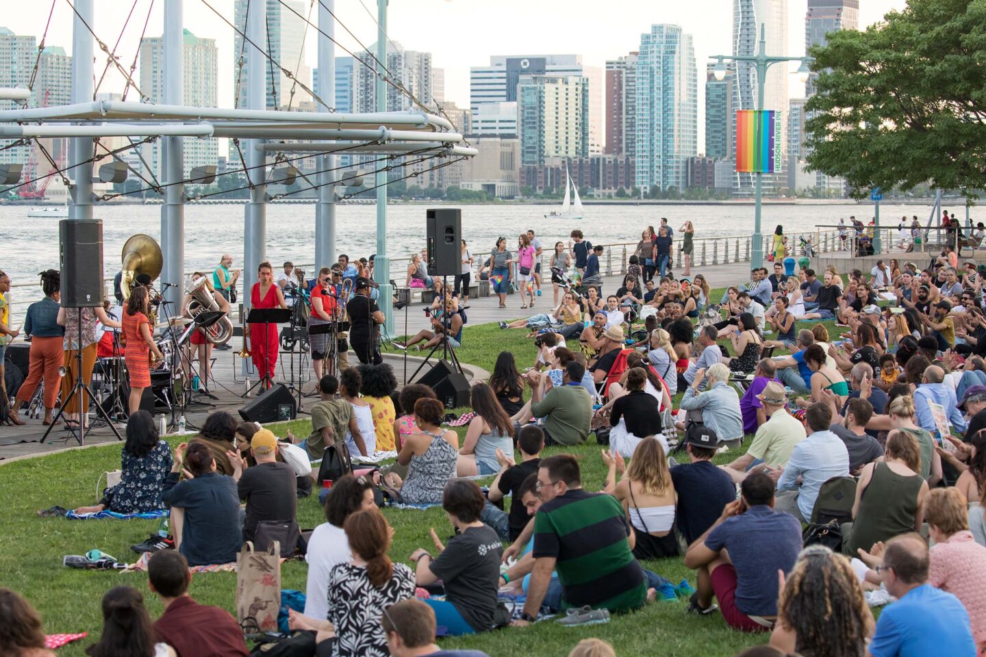 A group of music fans sit on Pier 45 listening to music as the sun sets
