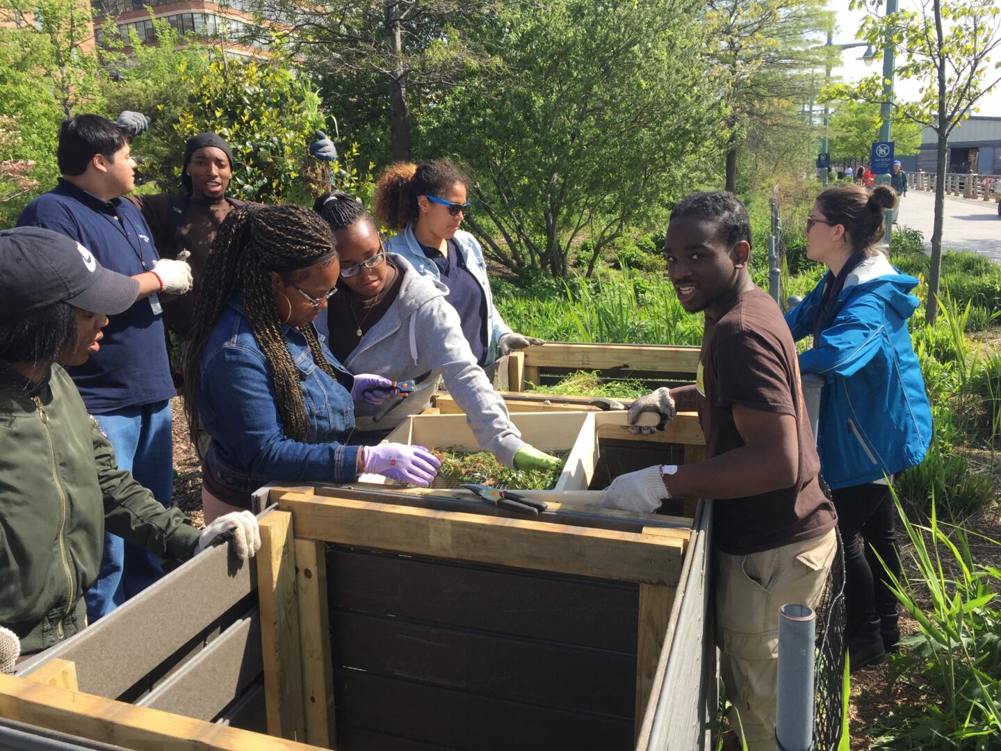 A group of students learn about composting and dig through the dirt