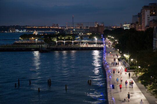 Purple street lights and the moon reflect against the nighttime waters of the Hudson River at HRPK's Greenwich Village Upland