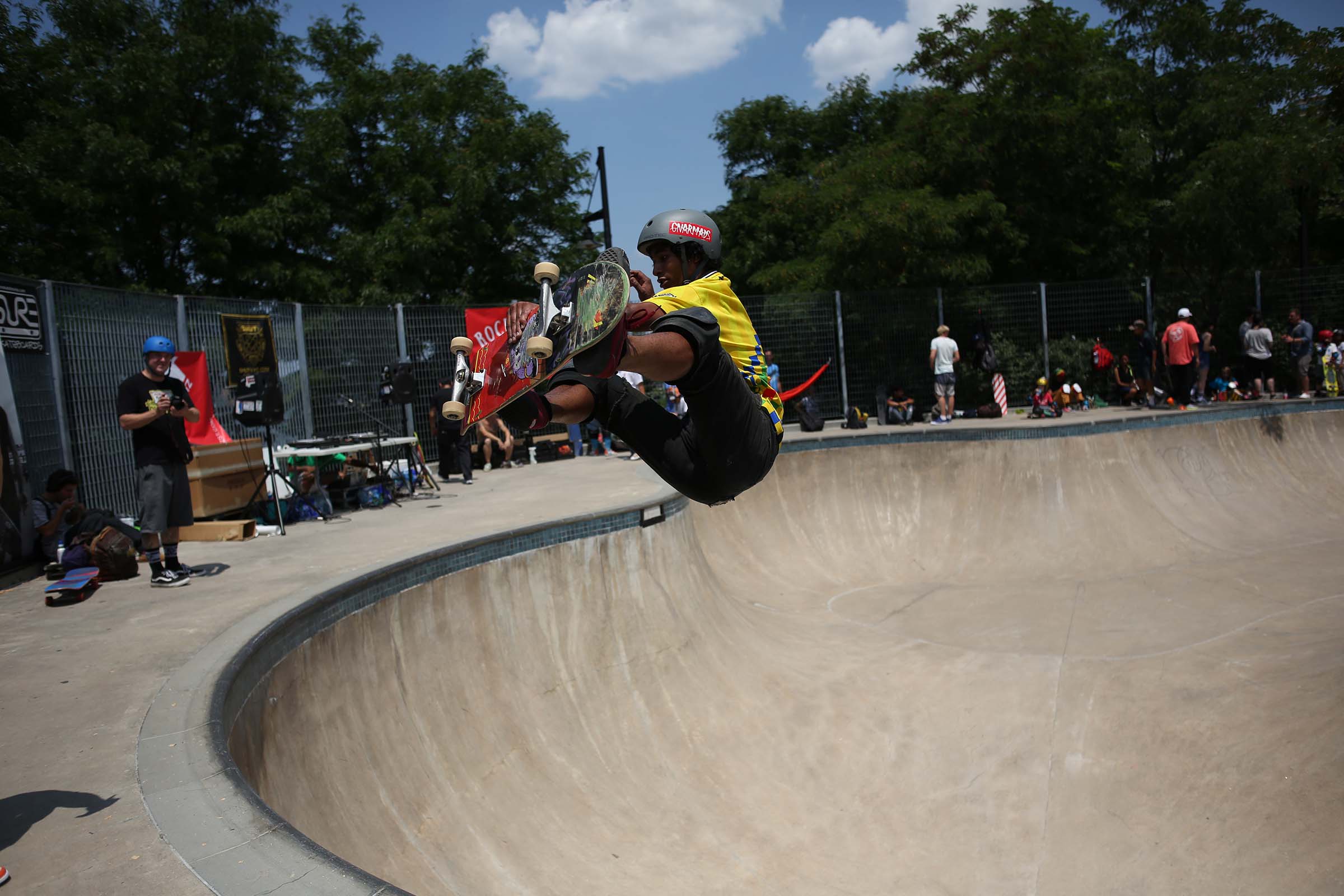 A skateboarder in yellow flies up after skating up the hill