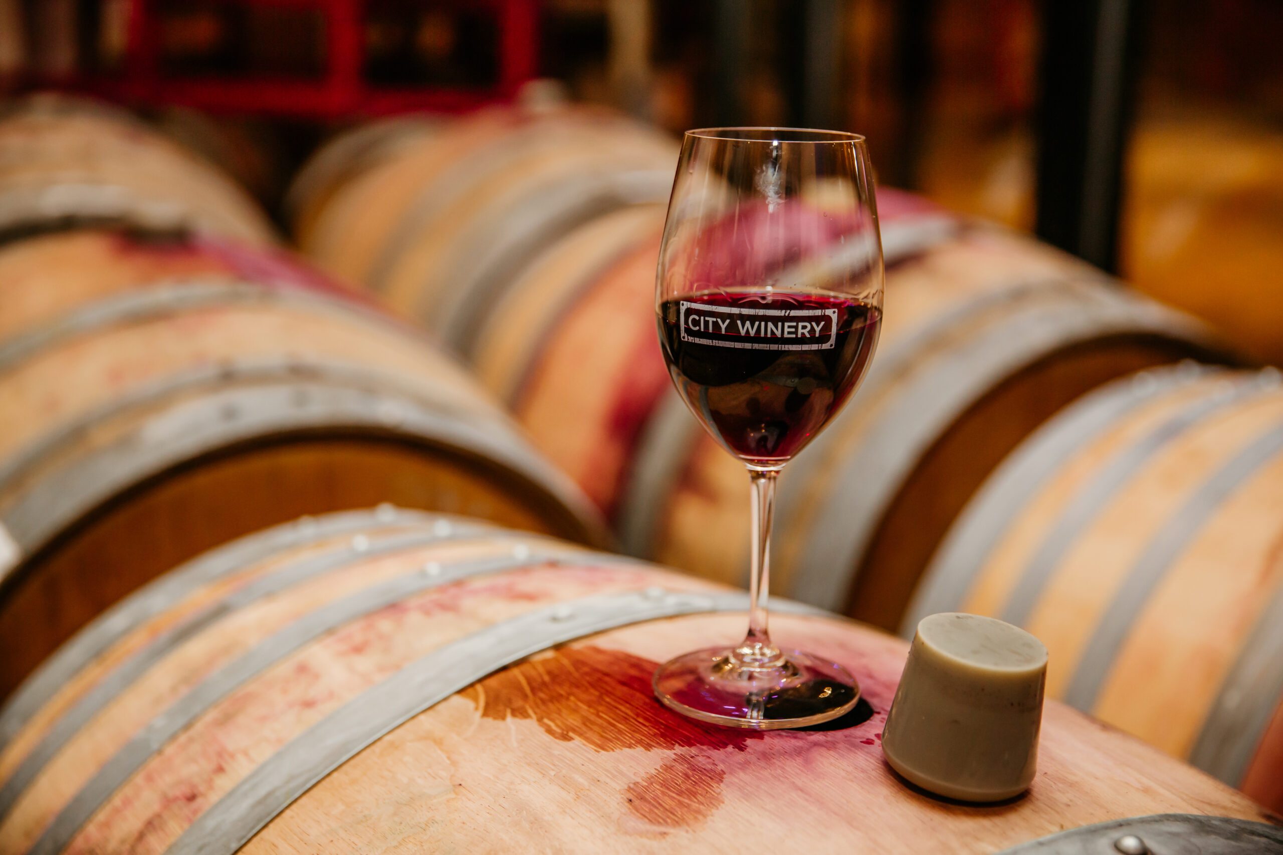 Red wine in glass sitting on wine barrels