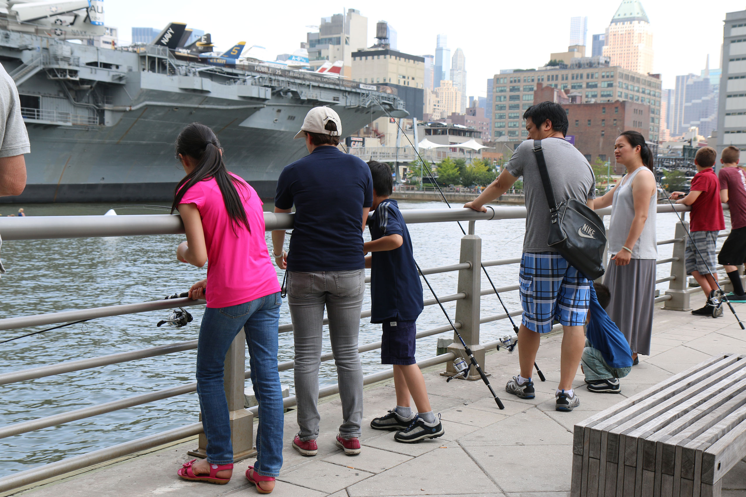 Park visitors fish near the Intrepid on Pier 84 at Hudson River Park