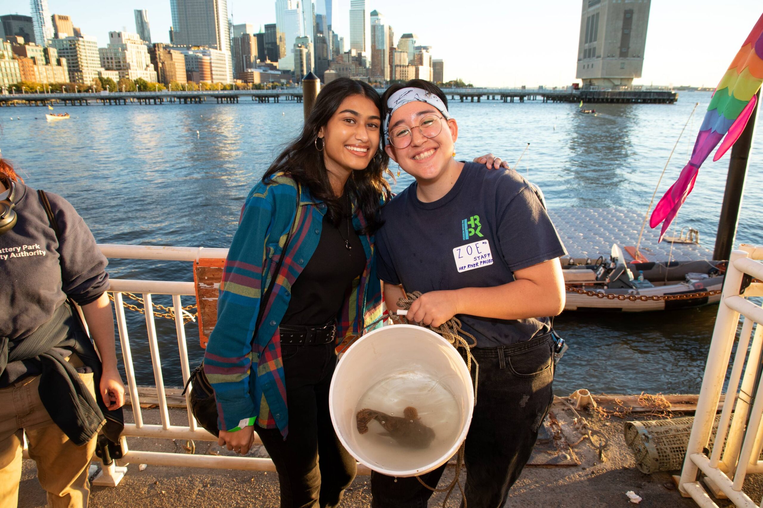 Two HRPK River Project staffers holding a bucket with a fish inside