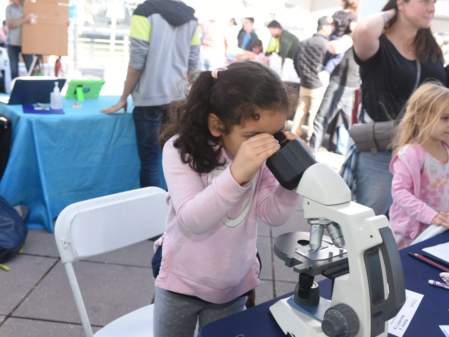 A girl looking through a microscope at SUBMERGE Marine Science Festival