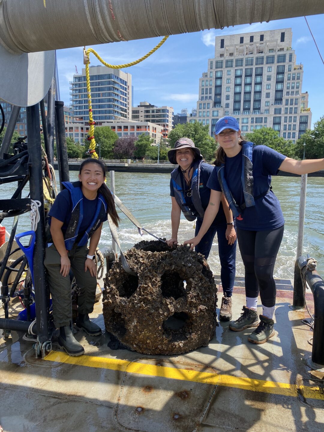 Hudson River Park's River Project team smiles with Reefball covered with oysters photographed during monitoring of Hudson River Park's Habitat Enhancement Project
