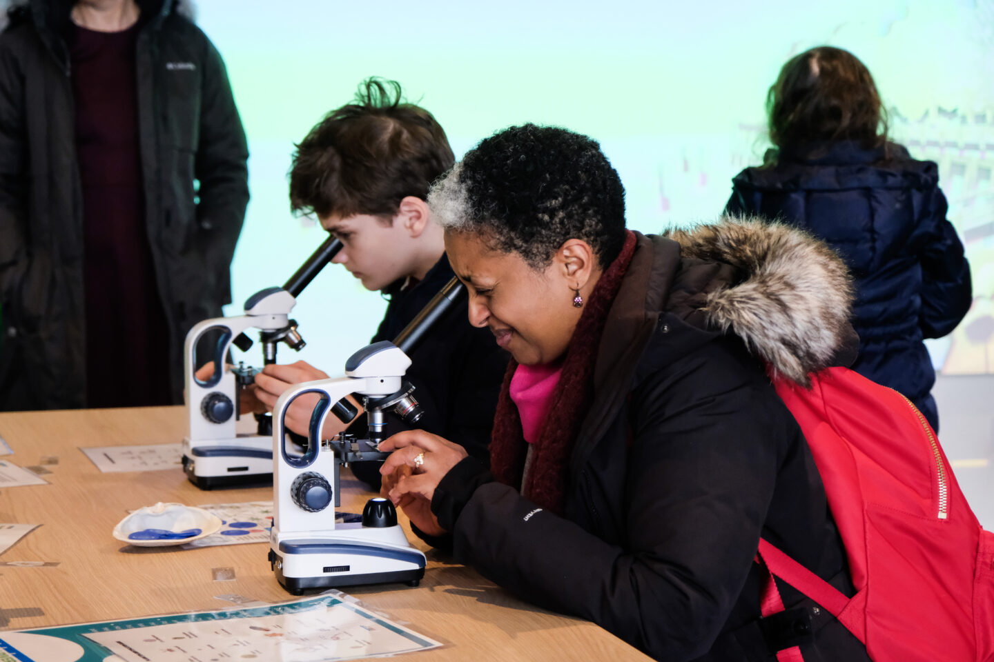 Two Discovery Tank visitors look through microscopes