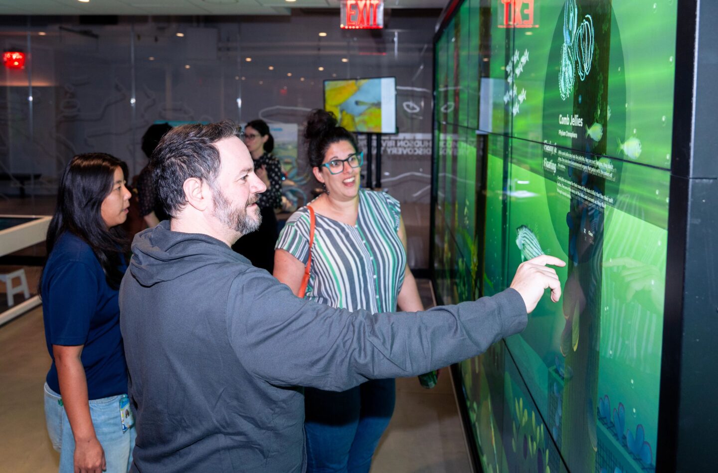 Two people interact with a touchscreen display wall at the Pier 57 Discovery Tank