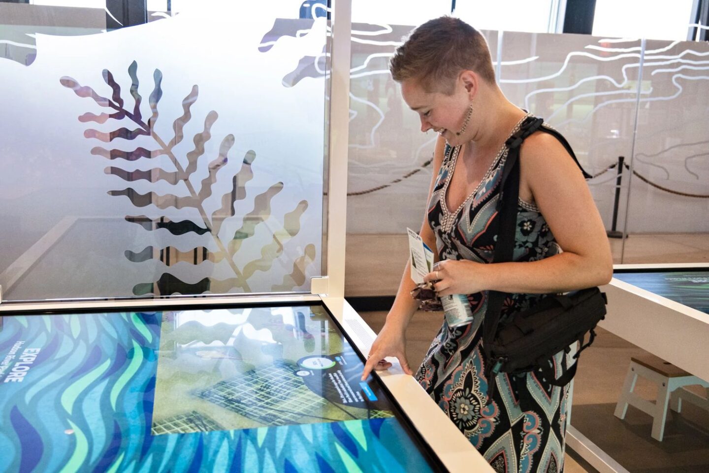 A person plays a game on an interactive tabletop touchscreen display at the Pier 57 Discovery Tank