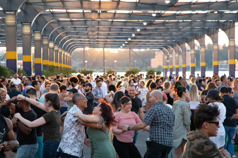 A large group of people dancing on Pier 76 during a Sunset Salsa event
