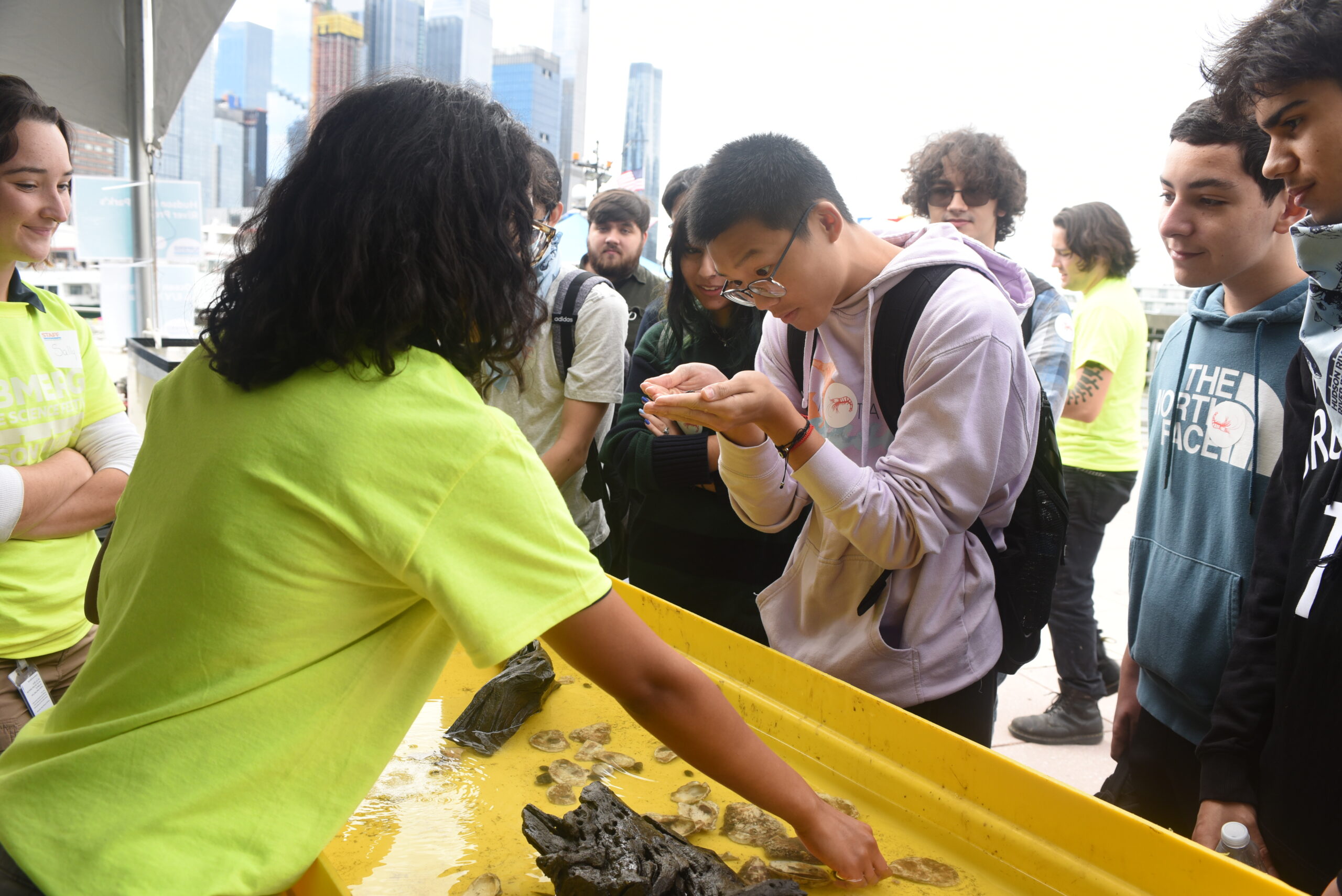 A high school student looking at a small Hudson River wildlife creature held in its hands