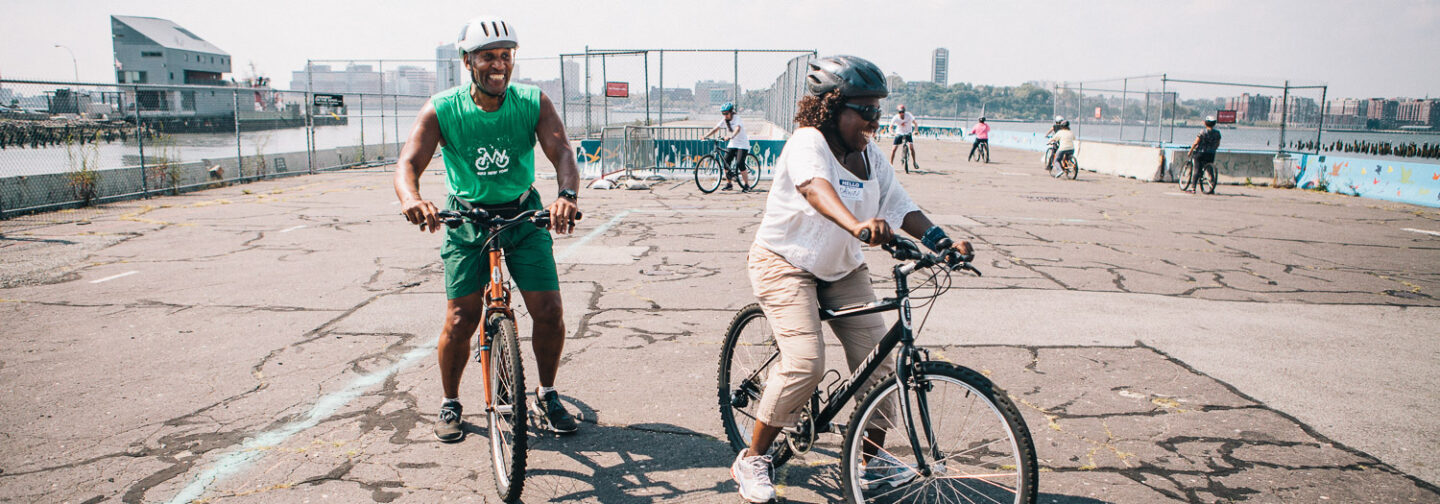 A Bike New York Bike Skills instructor riding alongside an adult student