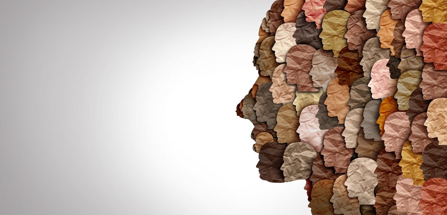 A collage of faces with many different skin tones viewed from the side; the collage forms the image of a larger face in profile.