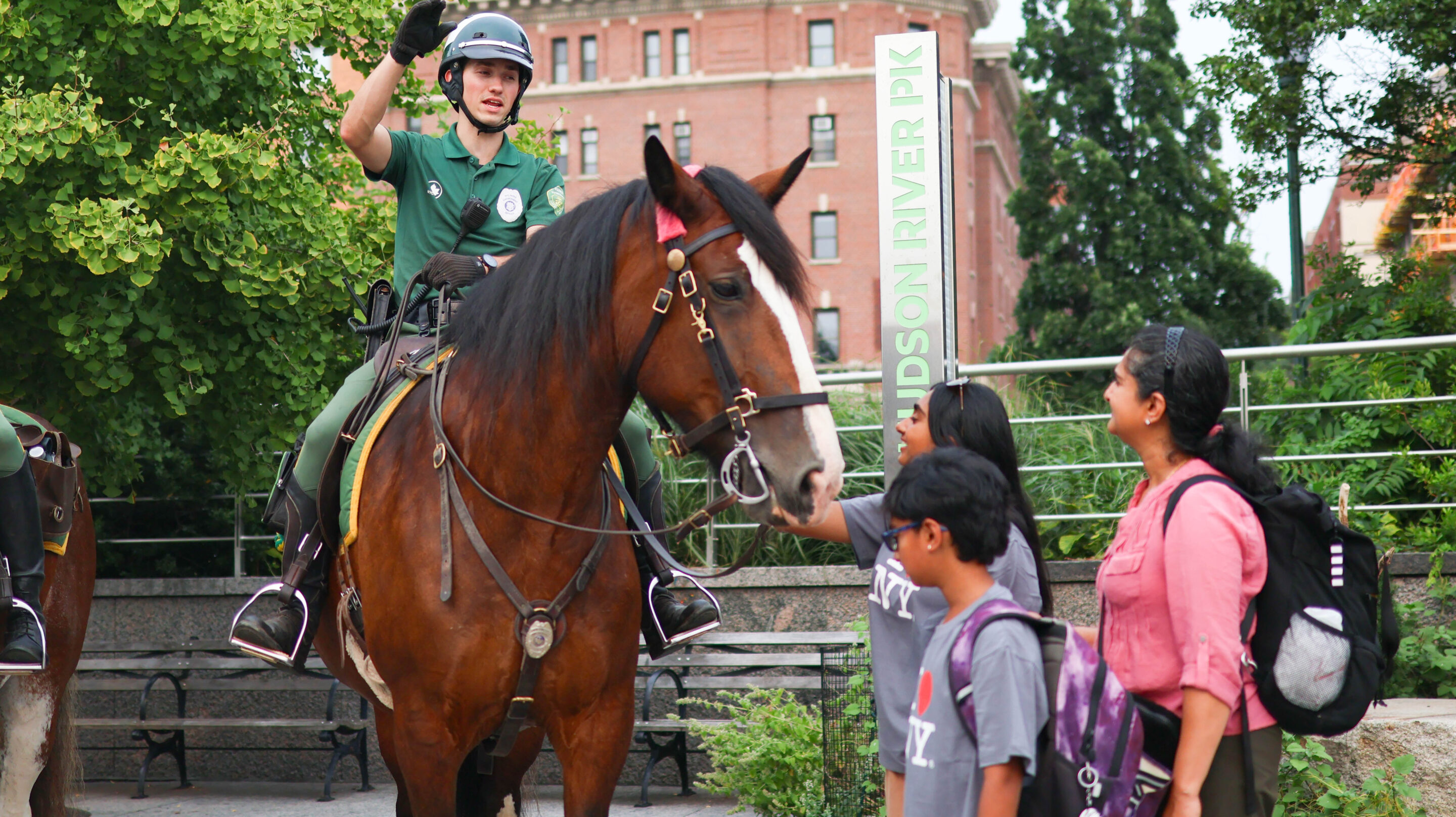 A Parks Enforcement Patrol officer on horseback speaks to three Park visitors