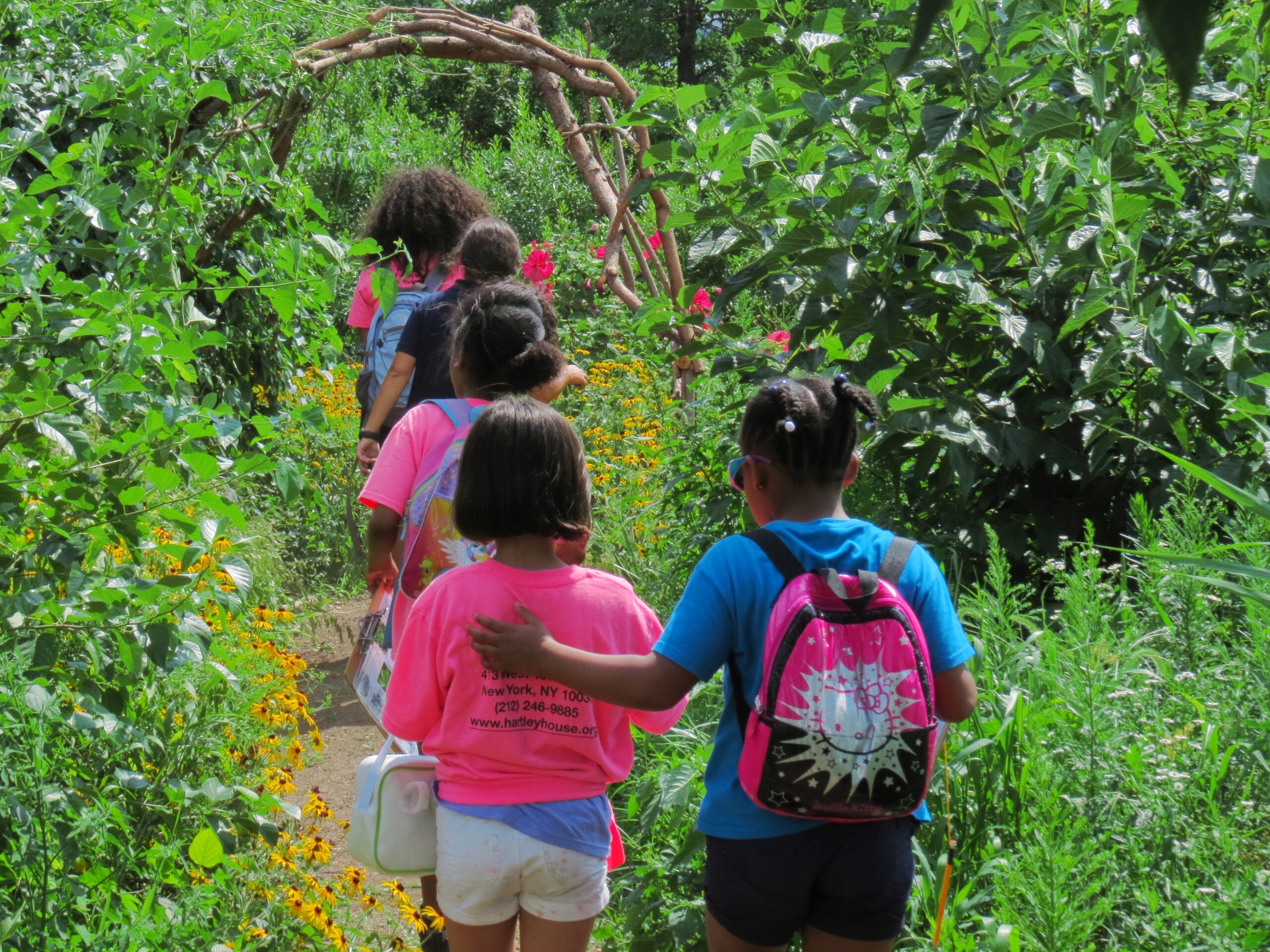 A group of students on a Nature Walk through Hudson River Park's Habitat Garden. One student has their hand on another's back to support them.