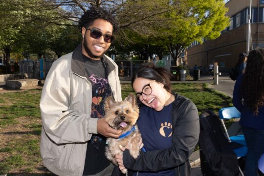 Two people smile with dog