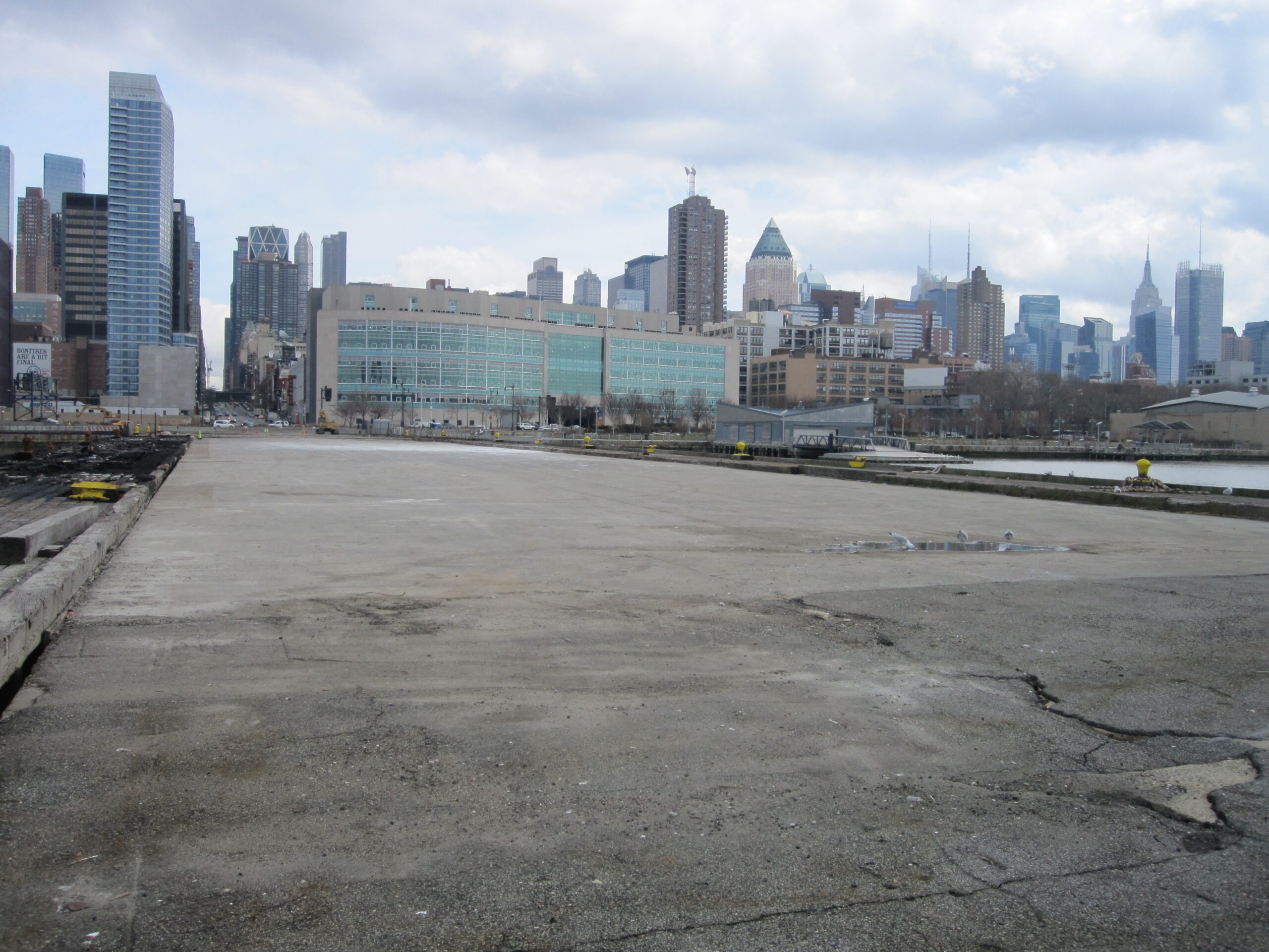 Pier 97 on the Hudson River prior to Hudson River Park's reconstruction of the pier. The pier is largely asphalt with a few cracks in it.