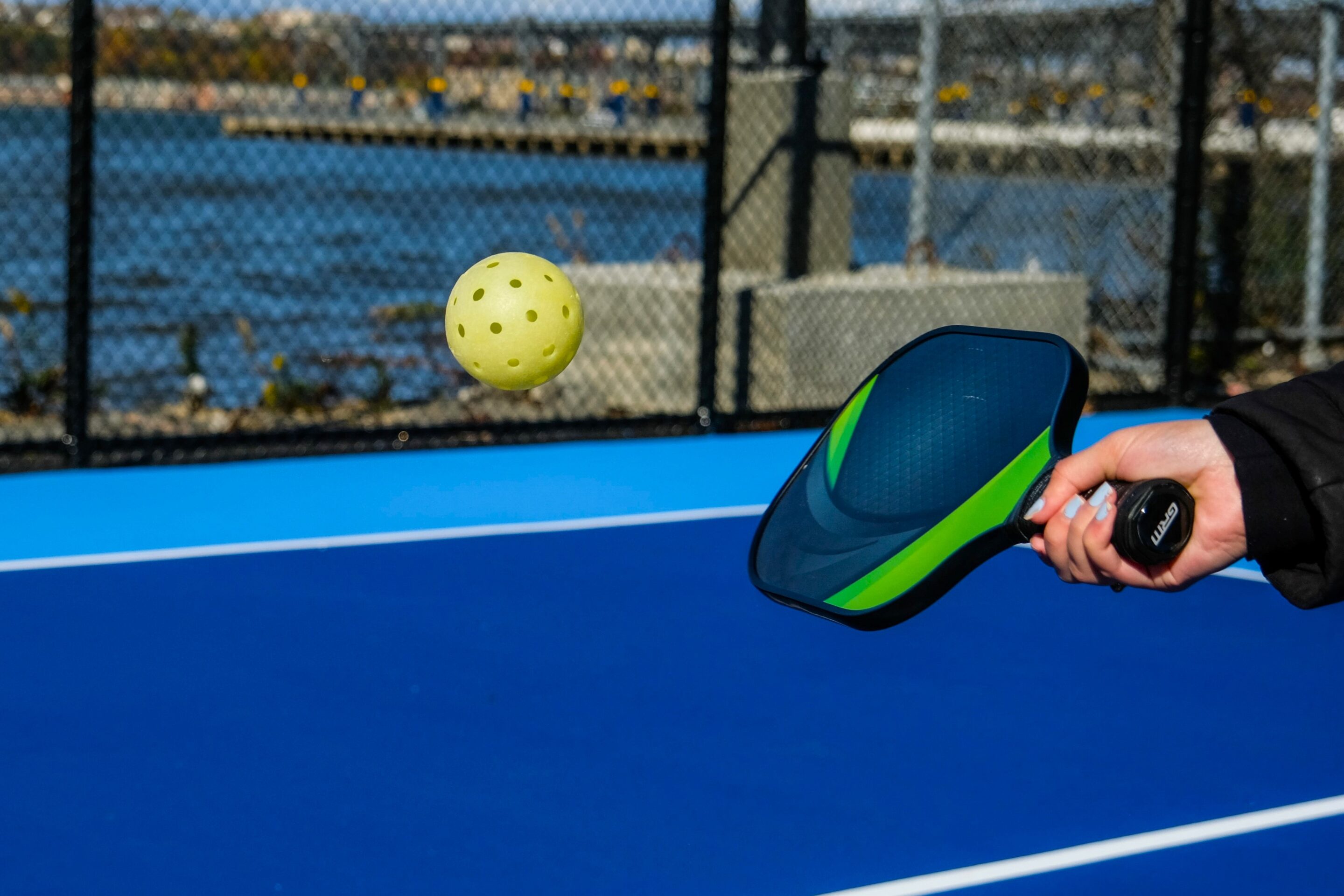 A close-up of a pickleball paddle being swung at a pickleball.