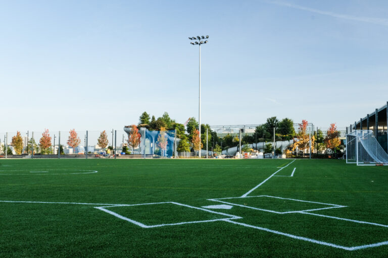 The turf athletic field at Gansevoort Peninsula looking down the first base line of the baseball field. Little Island is visible in the distance.