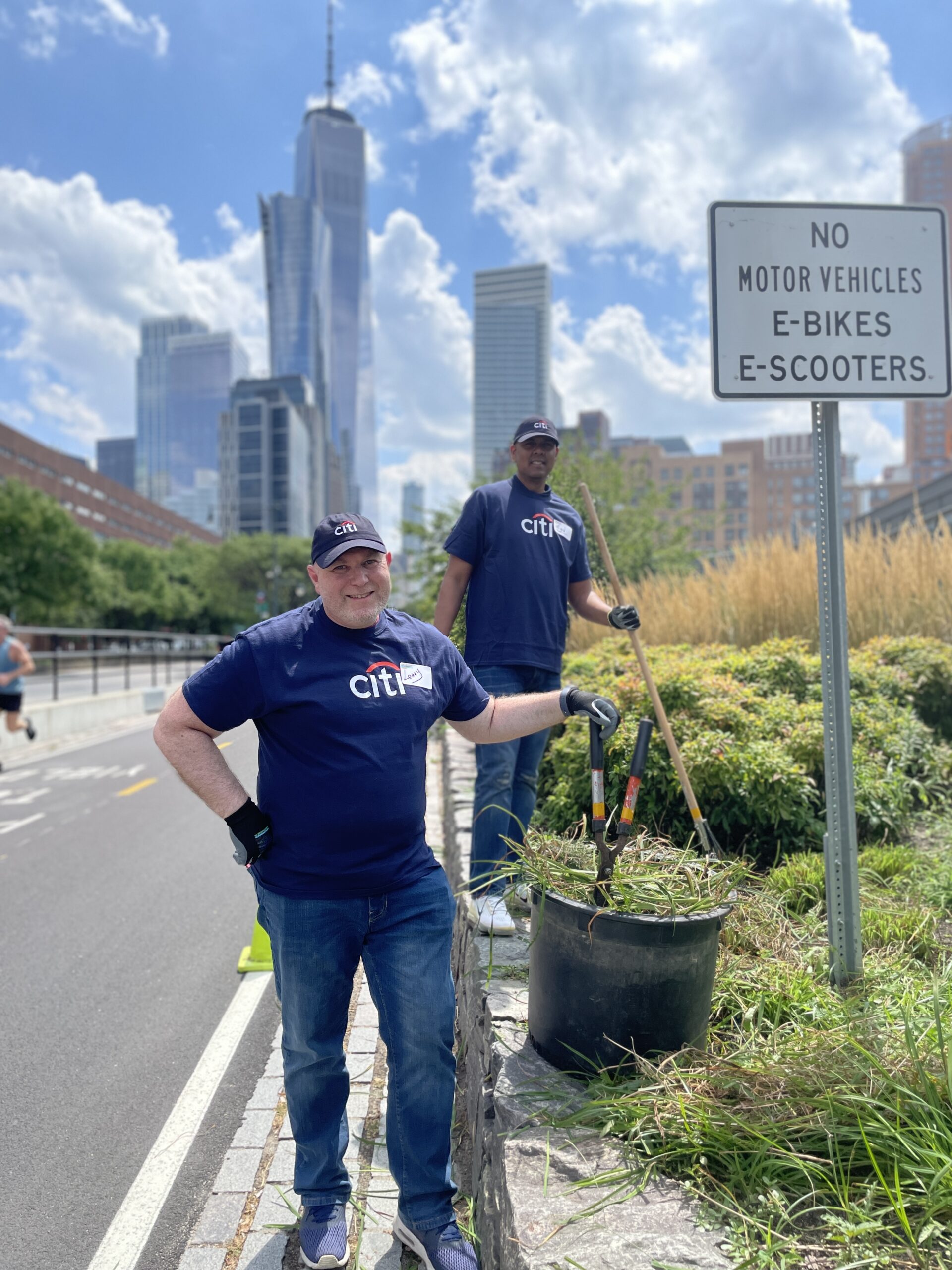 Two volunteers from Citi clearing plants and weeds along part of the Hudson River Greenway