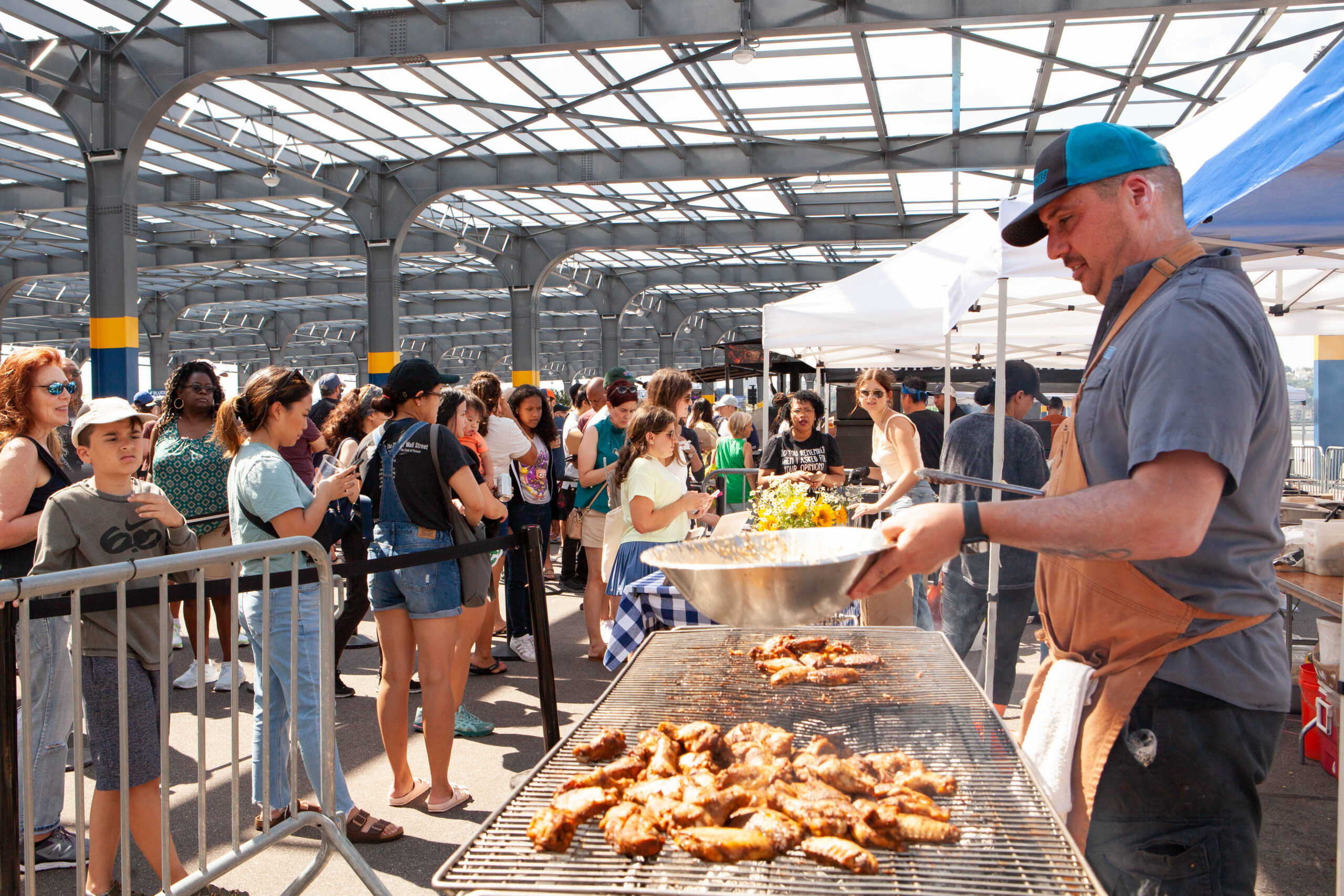A cook grilling meat in front of a line of customers at the Blues BBQ Festival on Pier 76